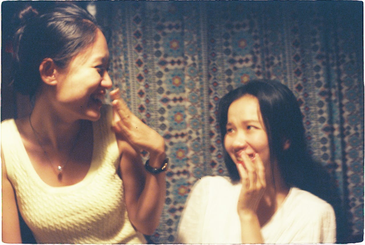 services-01 Two women sharing laughter and joy indoors with a vintage feel. Capturing moments of friendship.