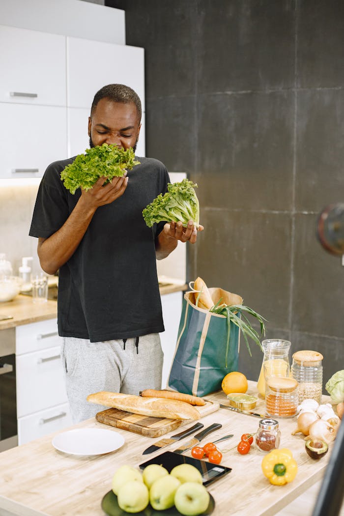 African American man enjoying fresh lettuce in a modern kitchen setting.